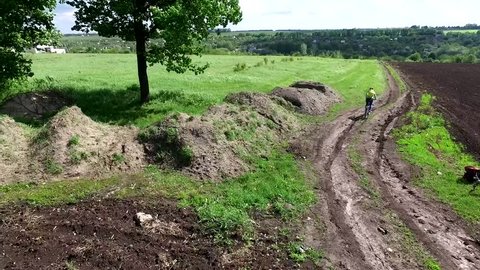 bycyclist riding bike in a field rolled road, aerial video