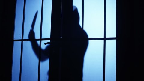 4K Silhouette of a killer or maniac with knife approaching to the door and entering to the room. Shot on RED Cinema Camera.