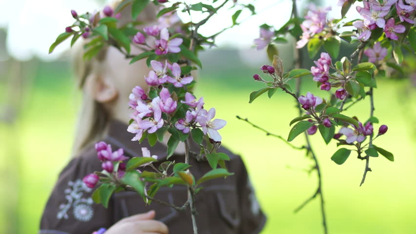 Two girls sniff the flowers on the tree