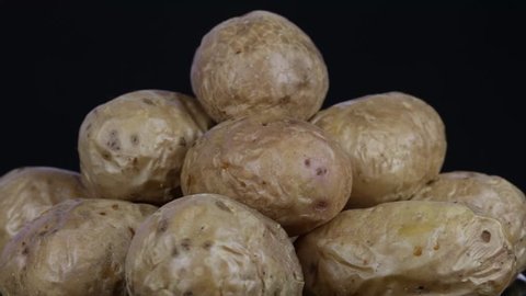 Ukrainian national dish is baked potatoes. Potato on a black background rotates, close up