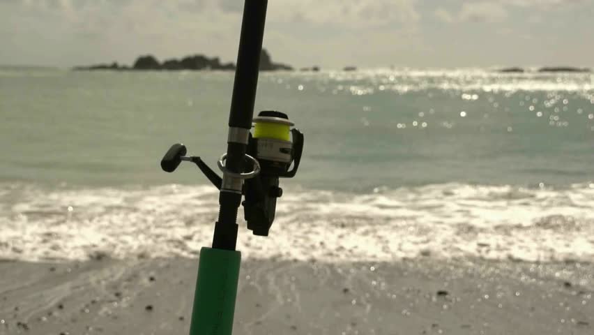 Fishing rod on the beach sitting in rod holder waiting for a fish bite.