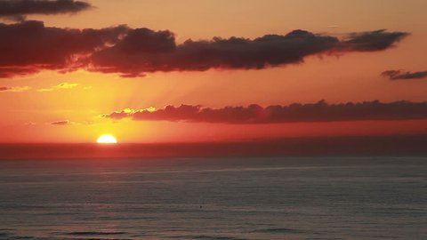 Sun is just beginning to rise above the ocean and clouds on the horizon of this beautiful sunrise view of sea and sky viewed from the 5th floor of a ocean front beach resort