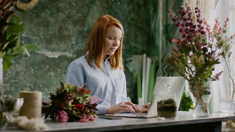 smiling florist typing on laptop