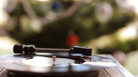 In vintage gramophone playing a vinyl record on a background of the Christmas tree. 
Christmas mood.

