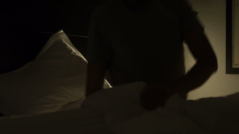 Man lays down in bed and turns off the light in the middle of the night. Man prepares to go to sleep