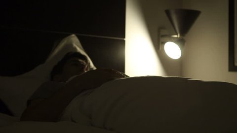 Person suffering from insomnia gets up from bed in the middle of the night