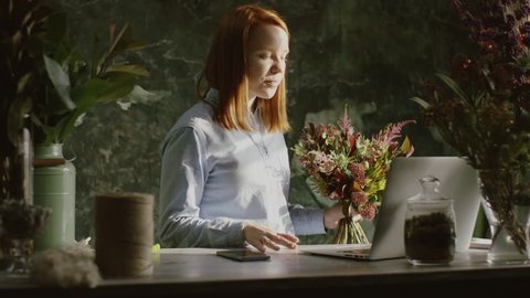 Beautiful female florist demonstrating bouqet in video chat