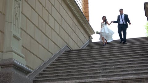 Wedding couple walking downstairs. Bride and groom holding hands. Value and love each other. Start family life.の動画素材
