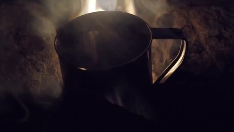 Iron mug on fire. Iron mug with water heated on the fire