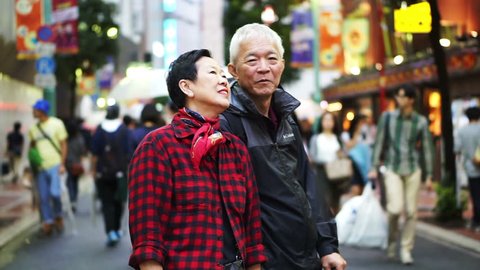 Tokyo, Japan - September 2016: Asian senior couple walking and shopping in Tokyo at night. Enjoying their trip in the city