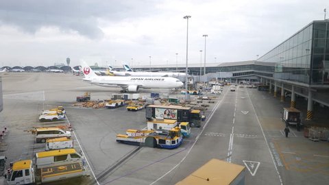 HONG KONG - APRIL 01, 2015: JAL airplane towed at ramp area, International airport terminal exterior. JAL JA613J aircraft (Boeing 767 - MSN 33849) slowly move and stop against modern terminal building