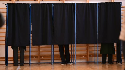 Unrecognizable people casting their votes inside voting booths during elections