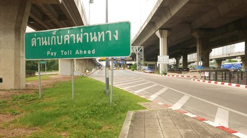 BANGKOK - MARCH 26, 2015: Toll gate ahead green road sign, Thai language, dolly camera move forward. Sirat Expy (toll road) entrance from Asok-Din Daeng Road, Khwaeng Makkasan area, Khet Ratchathewi