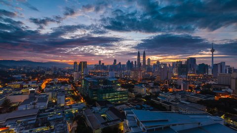 Time lapse: Beautiful and dramatic sunrise view of the Kuala Lumpur skyline overlooking the national landmarks, the Petronas Towers and Kuala Lumpur Tower. 4K UHD.