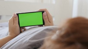 Woman at home relaxing in bed while holds green screen gadget 4K 2160p 30fps UltraHD footage - Greenscreen display smart phone in female hands 3840X2160 UHD video