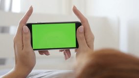 Greenscreen display smart phone in woman hands 4K 2160p 30fps UltraHD footage - Female relaxing in bed while holds green screen gadget 3840X2160 UHD video