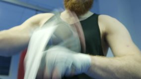 Fighter preparing for training, wrapping hands with boxing wraps