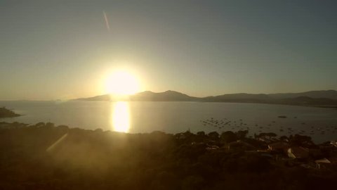 Aerial evening bird view coastline party island beautiful and romantic sunset sun moving down behind mountains in background showing apartments on hill and boats for anchor in sea amazing sundown 4k