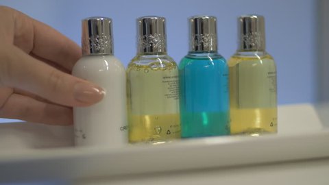 Close-up shot of housekeeper placing set of four bottles in the hotel bathroom. Shampoo, hair conditioner, body wash and lotion