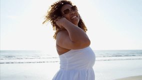 Portrait of happy voluptuous African American female in casual clothes having fun on vacation at a beach resort at sunset RED DRAGON