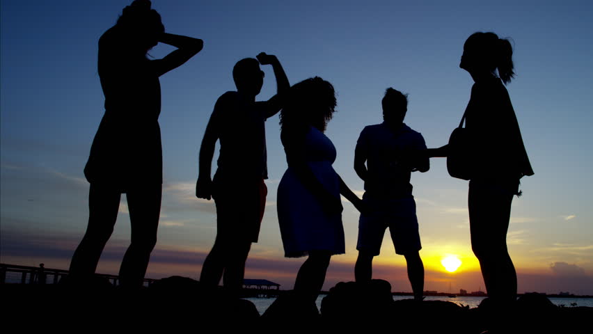 Silhouette of young people dancing and playing the guitar on ocean beach at sunset RED DRAGON | Shutterstock HD Video #22436335