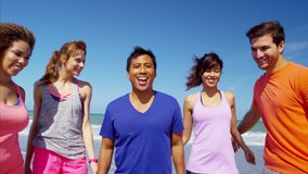 Portrait of young multi ethnic college students in colourful sportswear relaxing together by ocean RED DRAGON