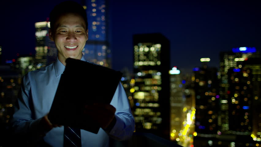Professional Asian Chinese male business consultant using touchscreen technology on rooftop at night Chicago RED DRAGON