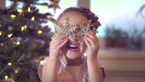Happy Christmas little girl having fun at home, near Decorated Christmas tree. Laughing child celebrating Xmas and New Year Winter Holidays, Playing with baubles. Slow motion 240 fps. Full HD 1080p
