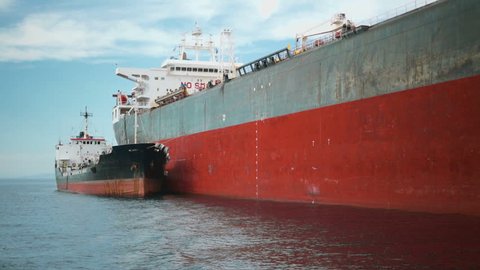 A tanker being refueled by a fuel barge in the open sea