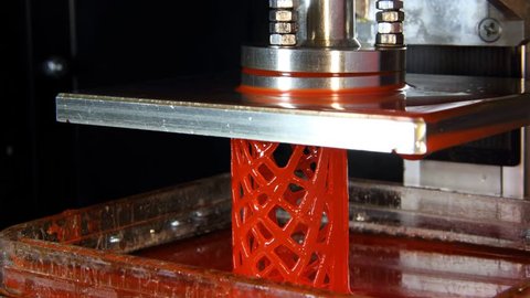 Red lattice bionic cylinder print using DLP machine, additive manufacturing process time lapse. Platform slowly lift up, polymer model created layer by layer, using photo polymerization technique