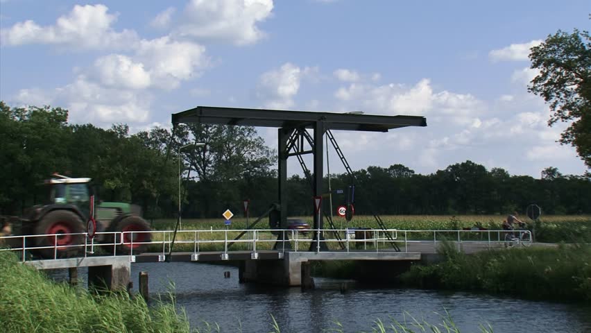VELUWE, THE NETHERLANDS - JULY 2016: Tractor with liquid dung tank rides across drawbridge in Dutch countryside.