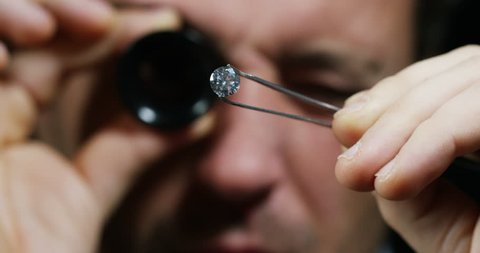 A goldsmith in jewelry checks the quality of luxury brilliant diamonds. The diamonds of high caliber shine the light and pure. Concept: Jewelry, luxury, glitz, gloss and goldsmith.