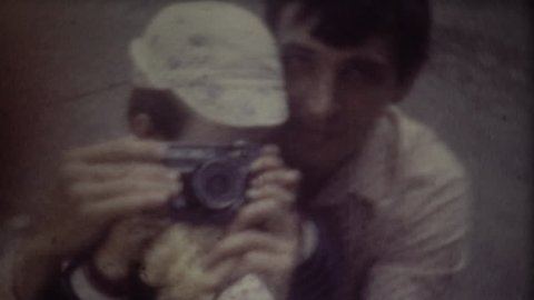 Father teaches son to photographing. Screenshot of 8mm retro camera. Family video archive.
