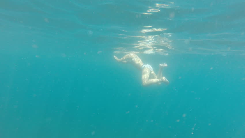 Slender girl slowly floats in the black sea. Swimming breaststroke. GoPro.