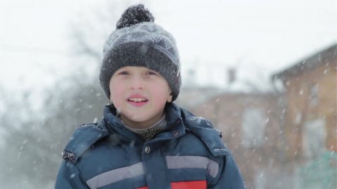 winter boy waved a hand/portrait of a cheerful boy in winter when snow falls