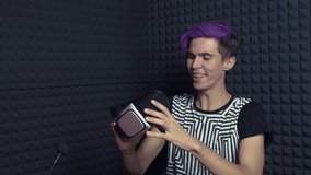 Young videoblogger with purple hair in web studio making review of vr glasses headset