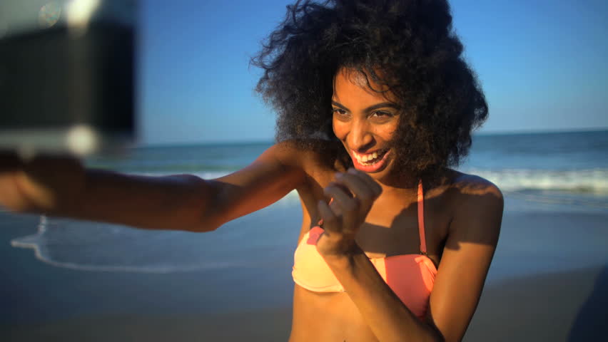 Young smiling African American female in swimwear having fun taking selfie on her beach holiday | Shutterstock HD Video #22474156