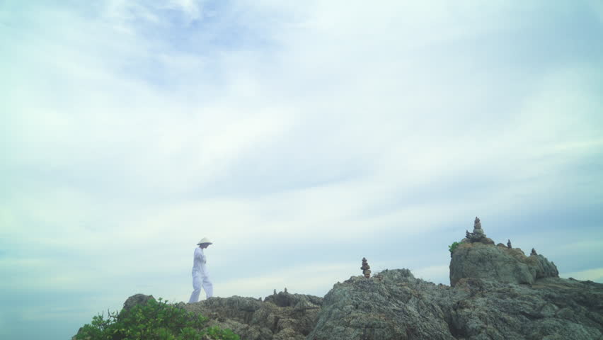 Man practicing breathing exercises on on the top of the rock