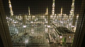 Time Lapse video in Medina Saudi Arabia. Muslim believers praying outside the al-Masjid an-Nabawi, prophet Muhammad’s Mosque, during hajj season. Minarets at the background at night.
