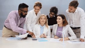 green renewable energy, teamwork, corporate and people concept - business team with papers and wind turbine model meeting and discussing project at office - Powered by Shutterstock - Get 15% off with code: PIKWIZARD15