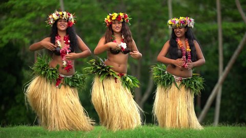 Polynesian girls in traditional grass skirts and flower headdress dancing hula style while entertaining barefoot outdoors Tahiti French Polynesia South, Pacific,