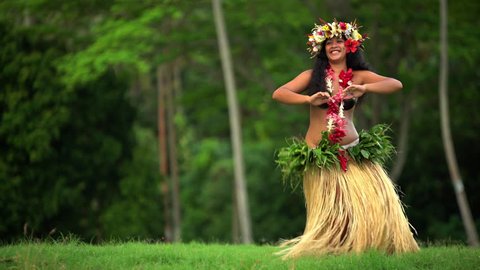 Polynesian graceful girl dancer in grass skirt and flower headdress dancing hula style while entertaining barefoot outdoors Tahiti French Polynesia