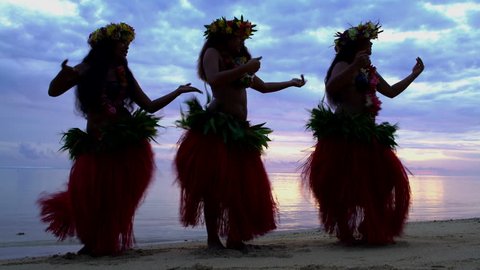 Group of beautiful graceful young synchronized Polynesian females dancing at sunset on the beach barefoot in traditional costume French Polynesia South Pacific