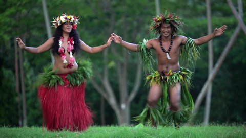 Beautiful young synchronized Polynesian male and female dancer entertaining in traditional costume barefoot outdoor French Polynesia South Pacific