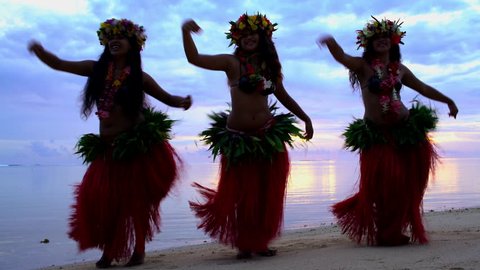 Young graceful Tahitian Polynesian females dancing on the beach at sunset barefoot in traditional hula costumes Tahiti French Polynesia South Pacific