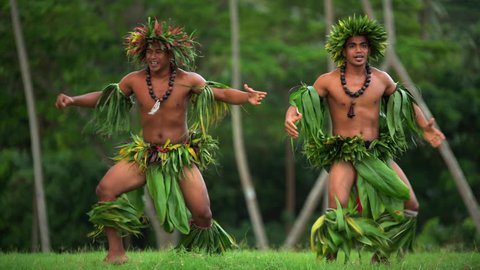Young strong Polynesian male warrior dancers entertaining in traditional costume barefoot outdoor French Polynesia South Pacific