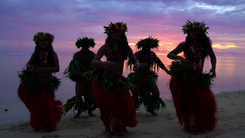 Young males and females in a group of Tahitian hula dancers performing at sunset on the beach barefoot in traditional costume Tahiti French Polynesia South Pacific