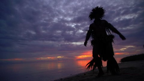Young Tahitian male at sunset performing war dance style hula dance outdoors barefoot in traditional costume Tahiti French Polynesia South Pacific