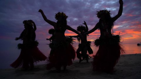 Young males and females in a group of Tahitian hula dancers performing at sunset on the beach barefoot in traditional costume Tahiti French Polynesia South Pacific