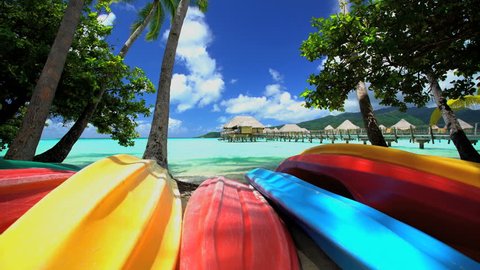 Canoe boats Palm trees Overwater Bungalows in tropical aquamarine lagoon a luxury vacation resort in Bora Bora South Pacific French Polynesia